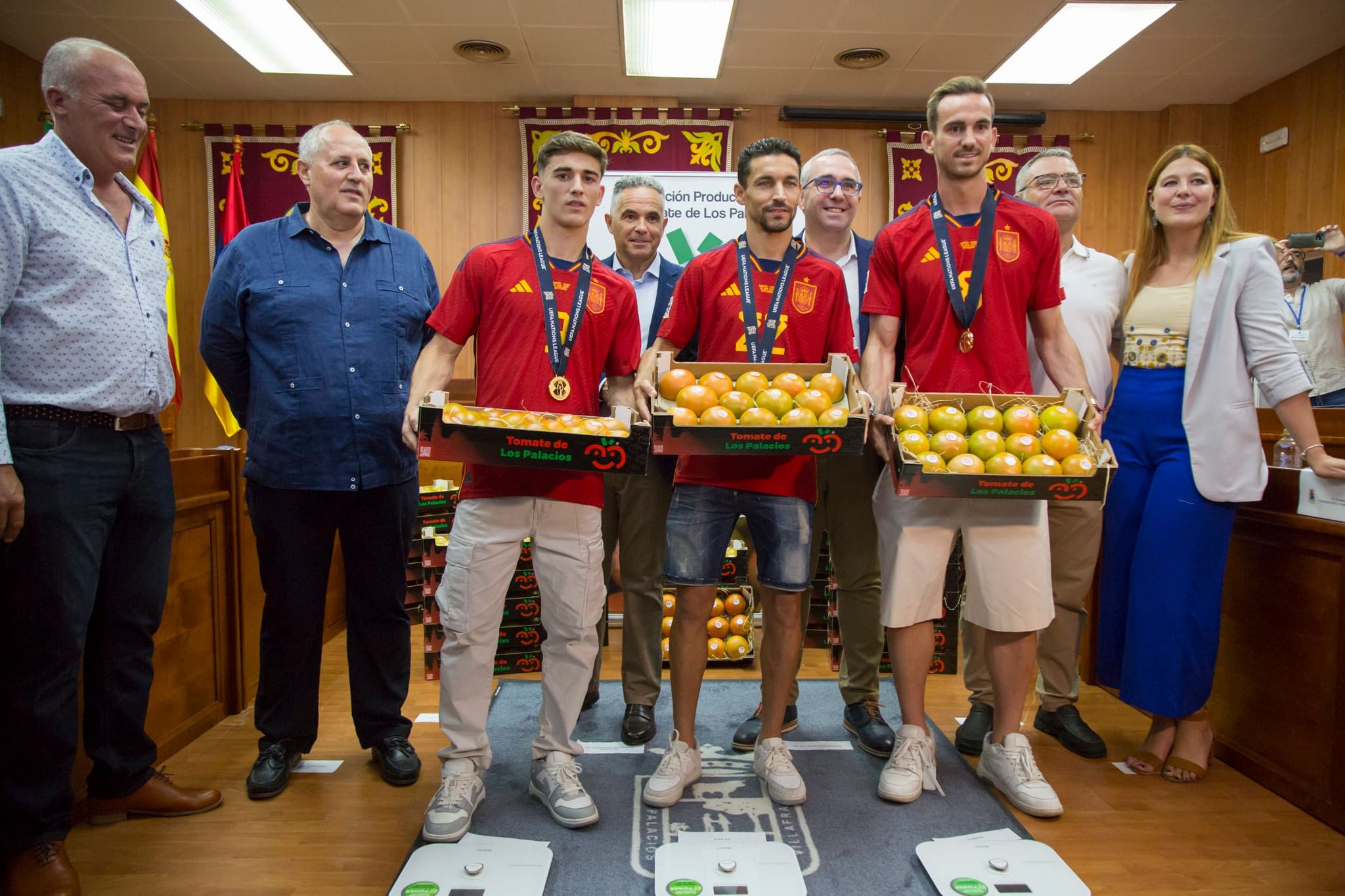 Gavi, Fabián y Navas posan con sus cajas de tomate tras pesarse para el regalo tras la recepción en el Ayuntamiento de Los Palacios.