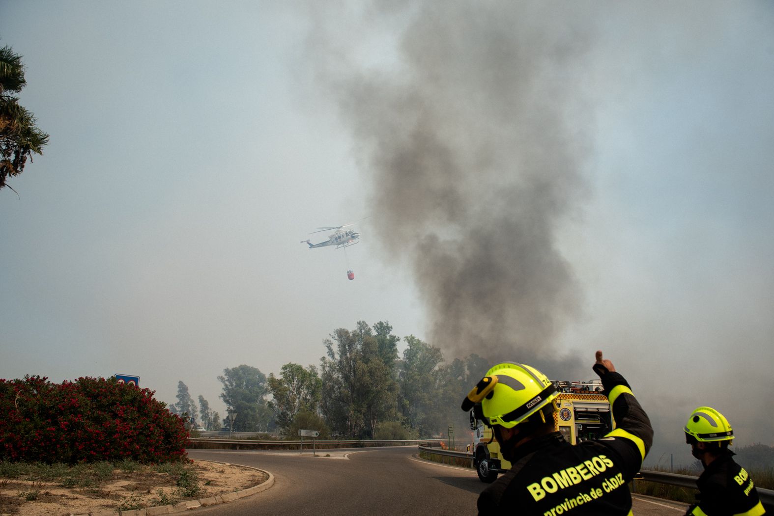 Un avión del Infoca actúa sobre una zona en llamas, en la tarde de este domingo en Puerto Real.