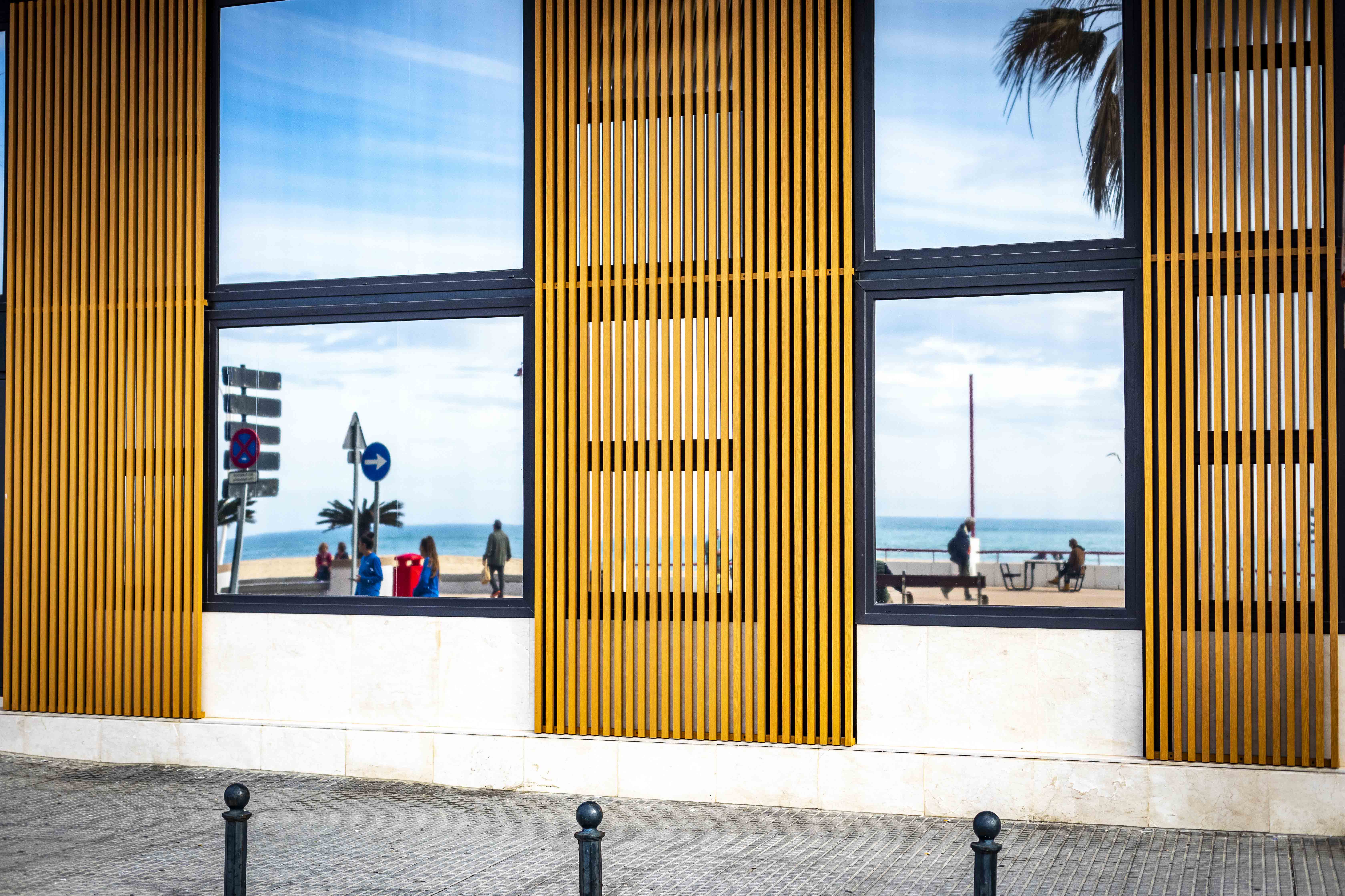 El Paseo Marítimo de Cádiz en invierno, reflejado en un edificio de apartamentos turísticos de la calle Brasil.