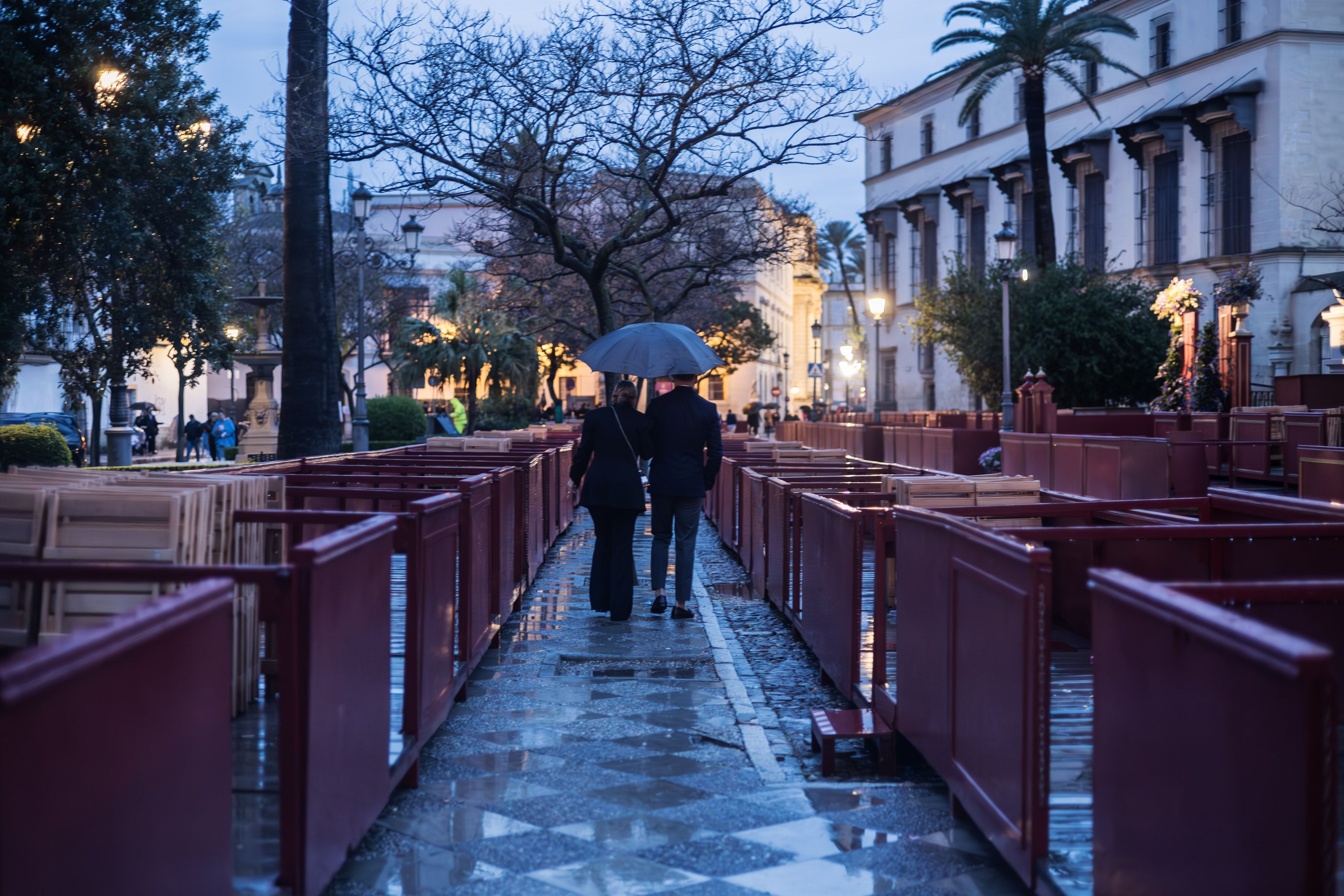 Una pareja paseando bajo la lluvia entre los palcos de plaza Aladro