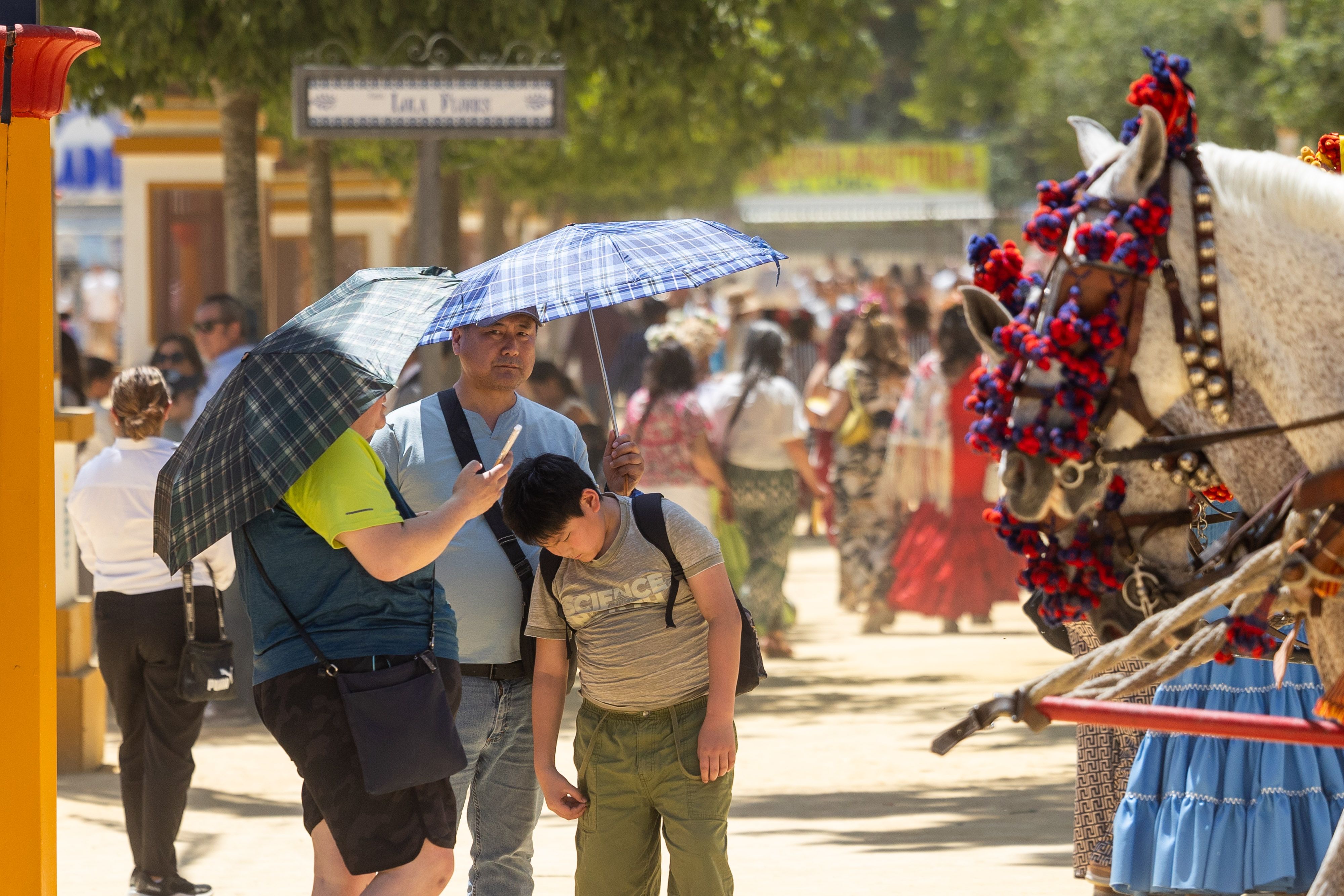 Feria de Jerez. Unos turistas se protegen con paraguas del sol en el Hontoria.