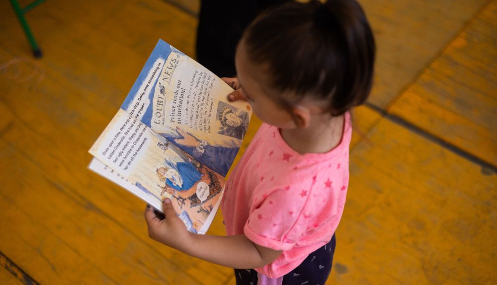 Una niña lee un cuento en la sede de Brote de Vida.