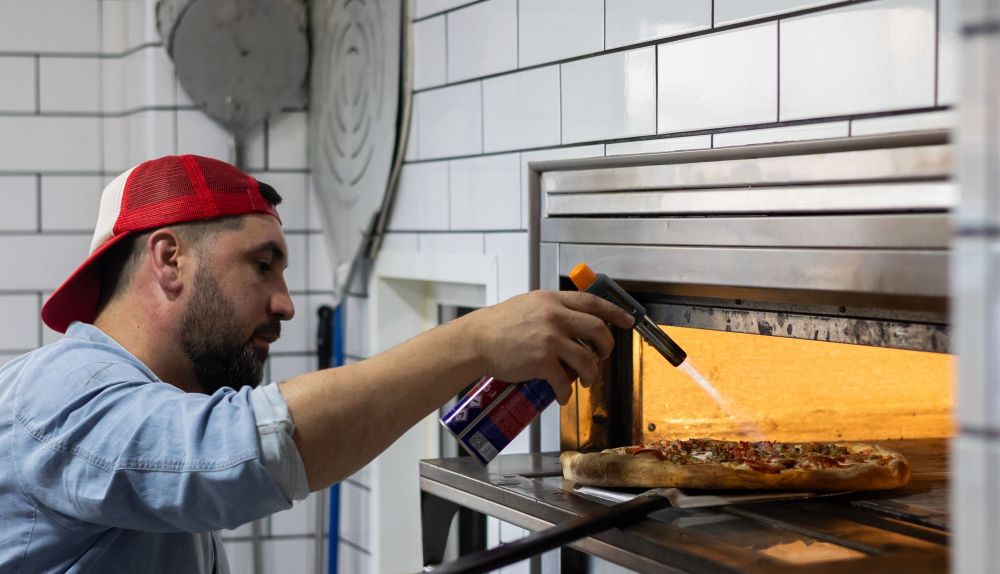 Pablo López, jefe de cocina, introduce una pizza en el horno.