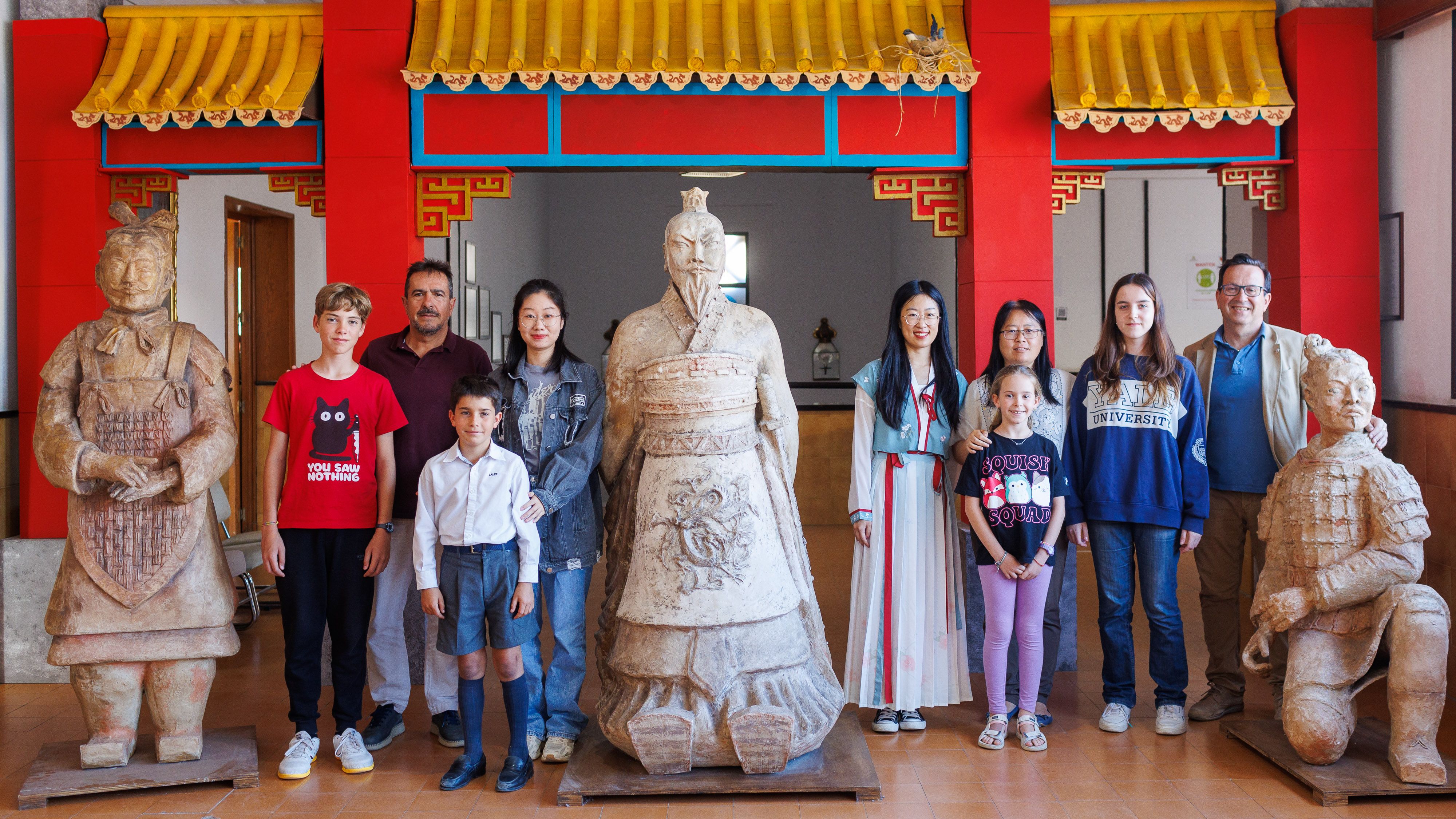 Alumnos, profesoras y responsables del centro posan junto a una réplica de la Gran Muralla China y de los guerreros de Xi'An en el IES Coloma.