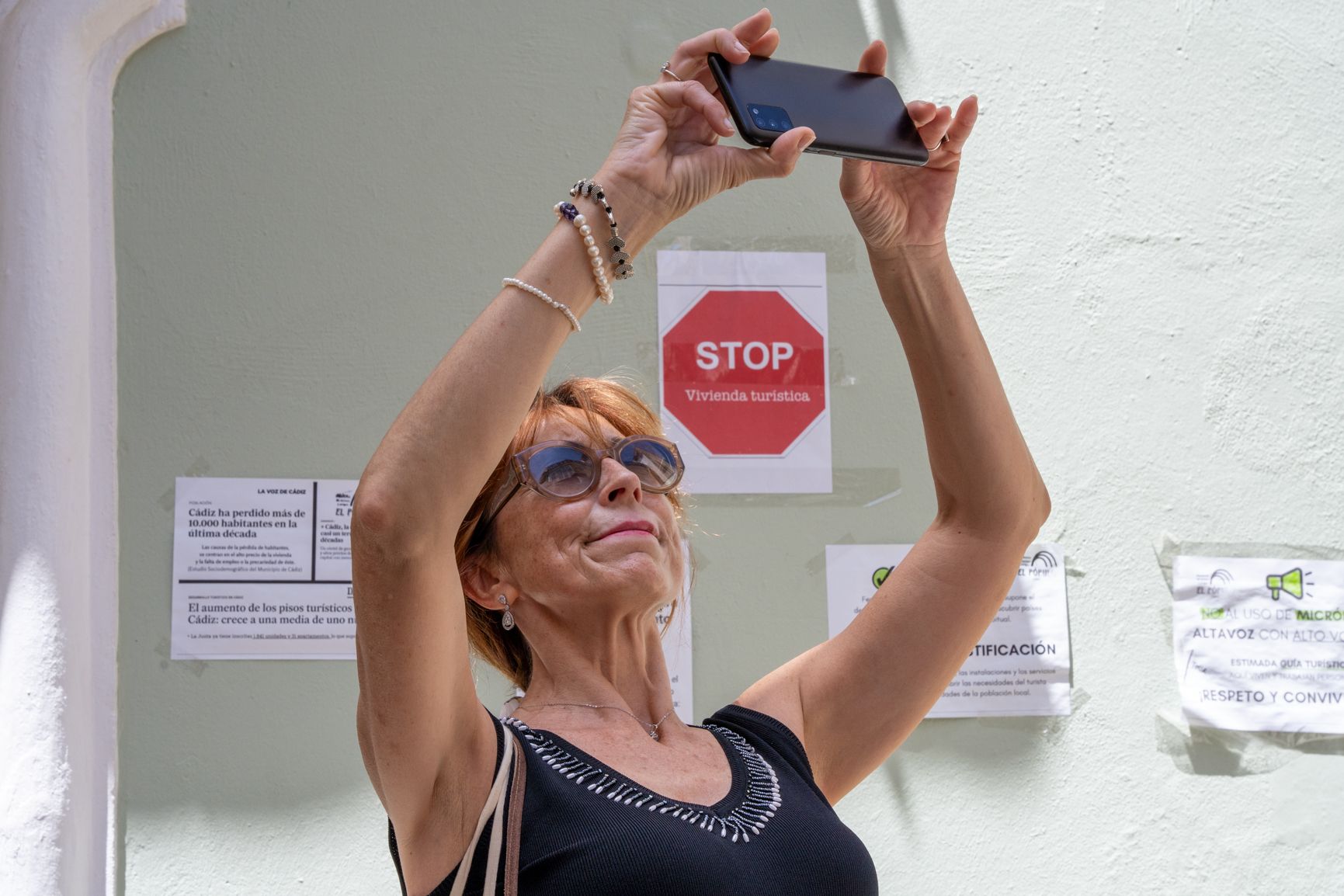 Una turista toma fotos en El Pópulo rodeada de carteles contra la "turistificación".