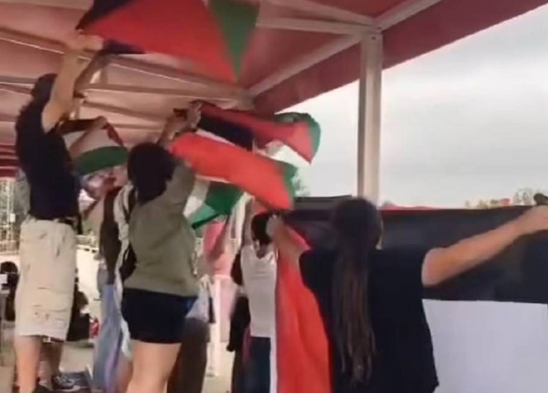 Los asistentes enarbolando la bandera palestina justo antes de la agresión.