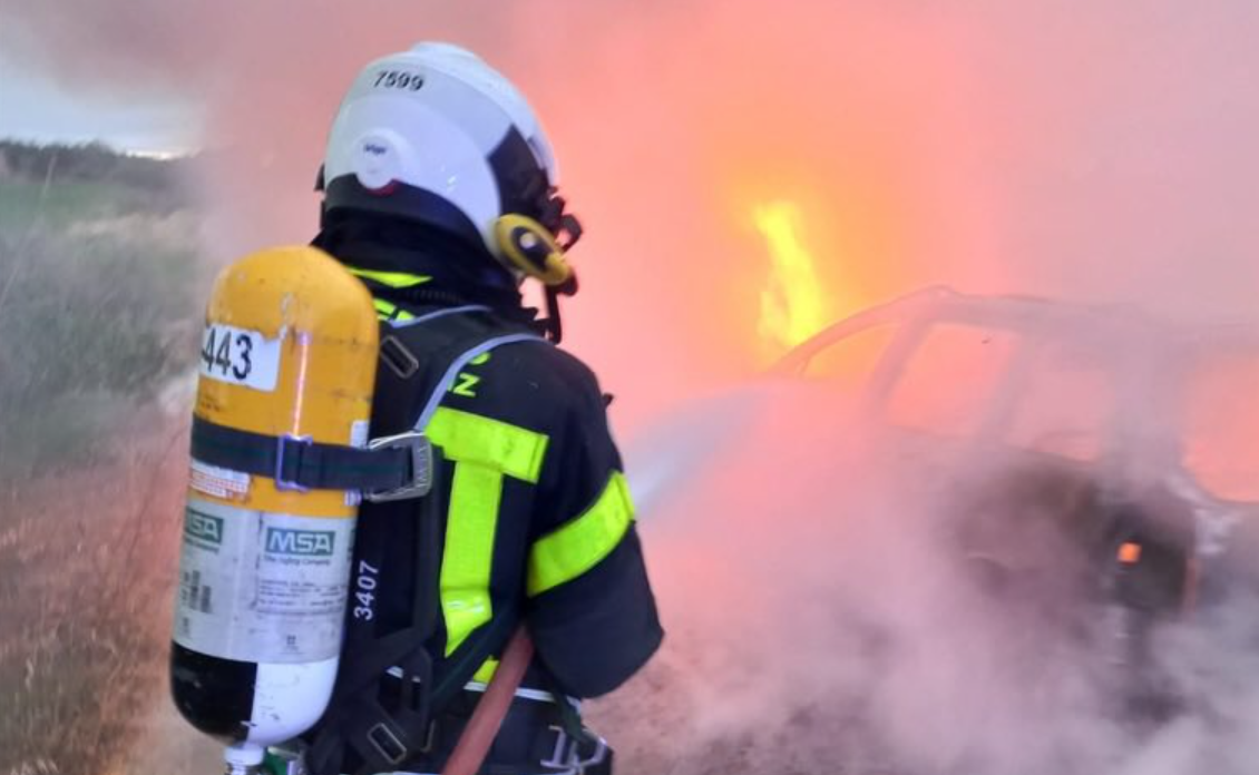 Un bombero actúa ante el incendio del turismo en la carretera del pantano de Arcos.