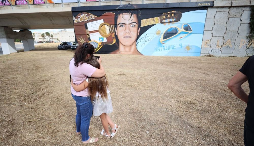 Dos jóvenes contemplan el grafiti de Migue Benítez en San José Obrero.