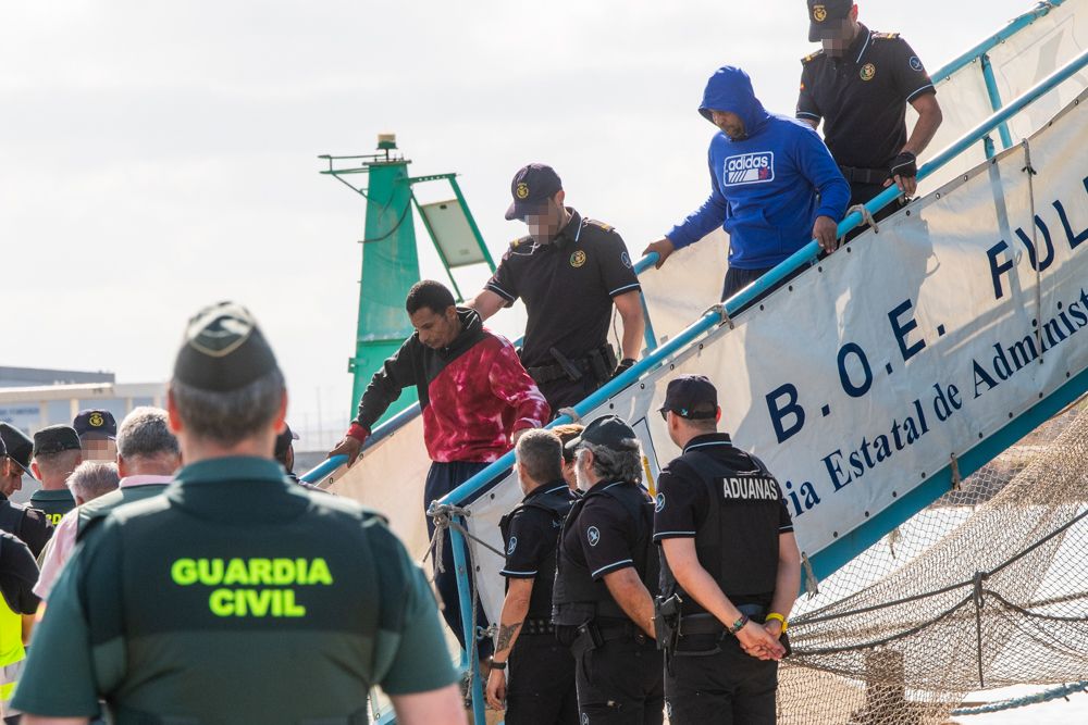 Dos de los cuatro detenidos, al desembarcar en Cádiz camino del furgón policial.  