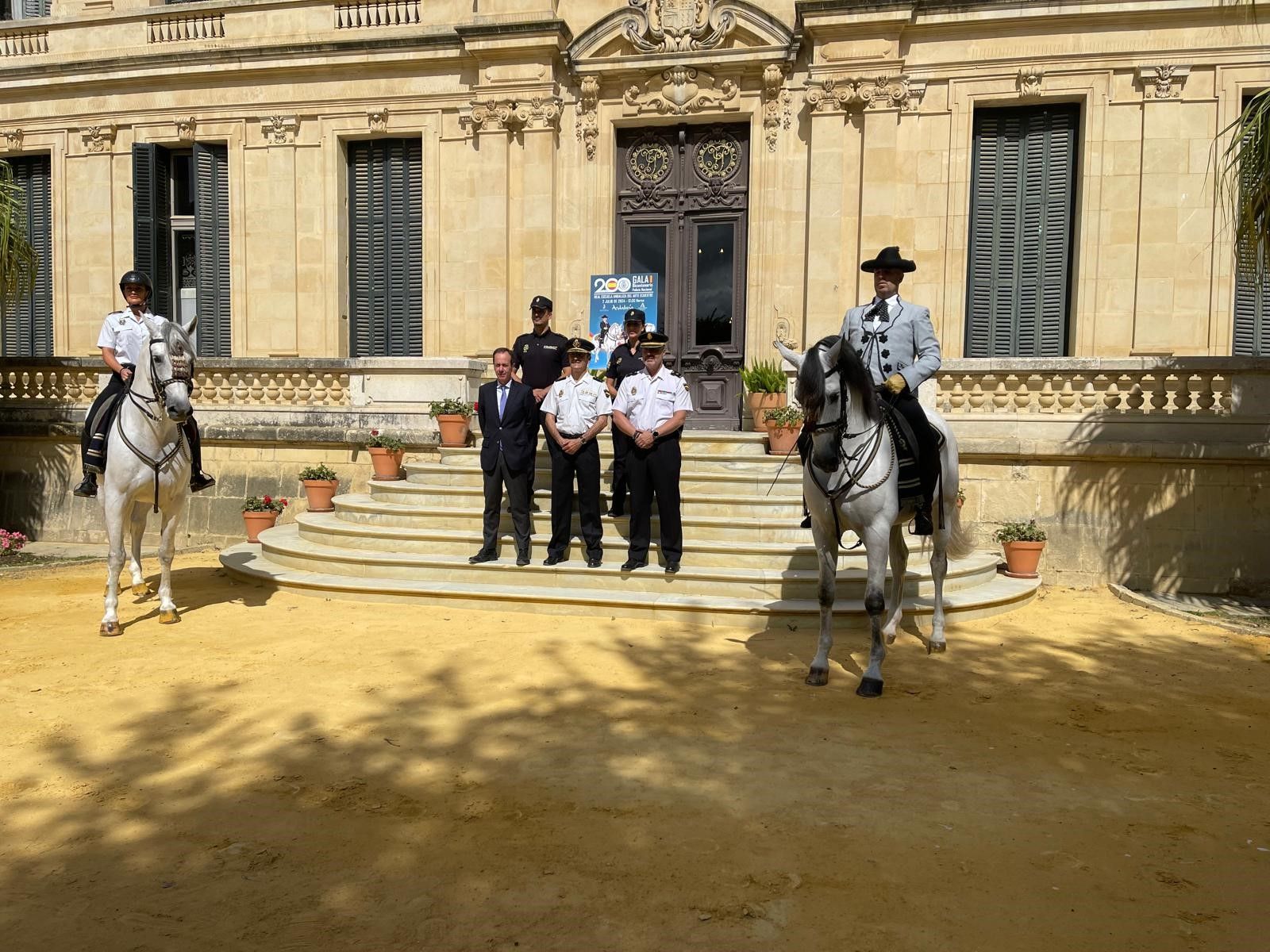 El comisario de policía de Jerez y el gerente de la REAAE en la puerta del palacio escoltados por jinetes de la institución.