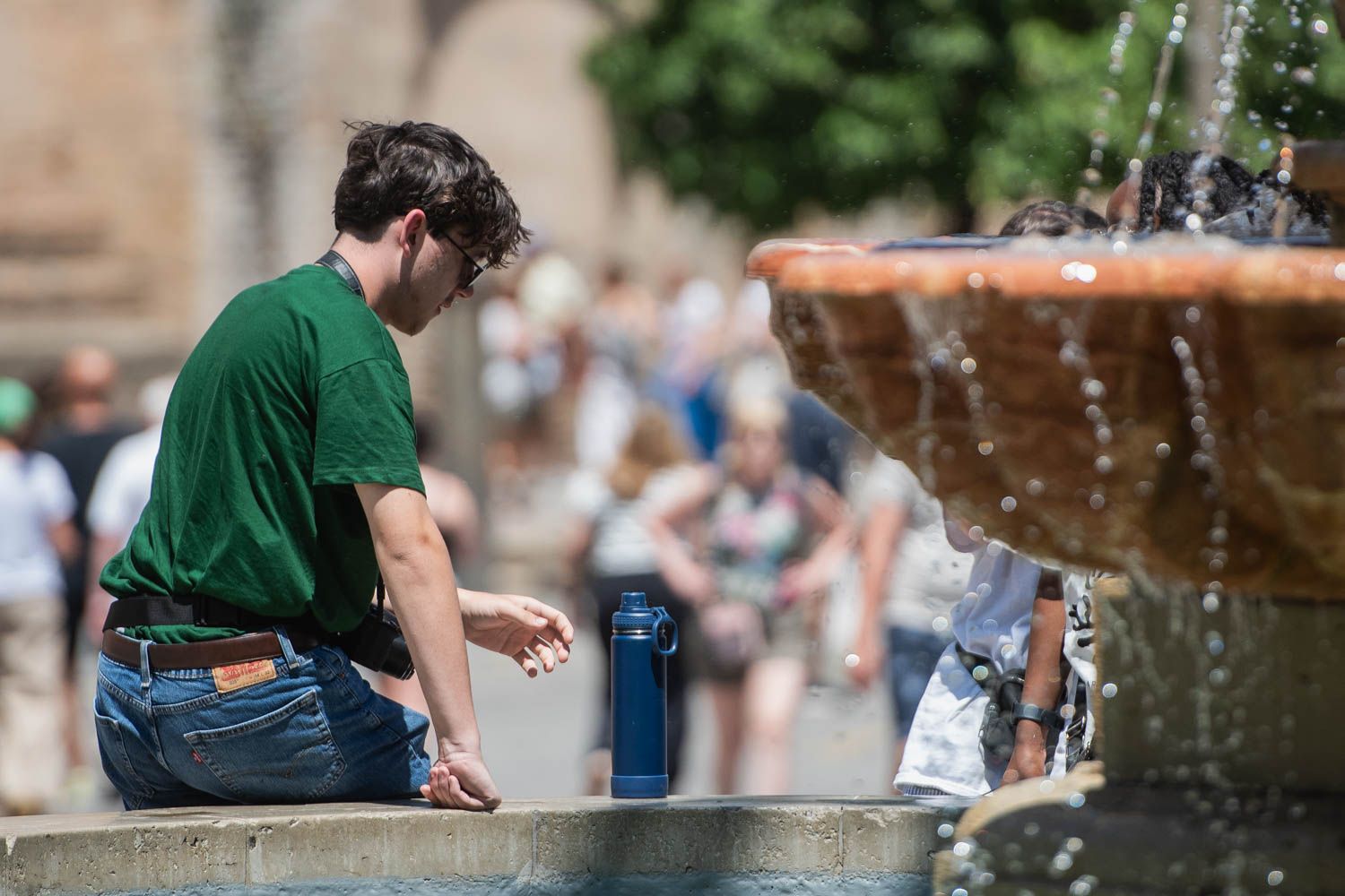 Un joven se refresca en una fuente durante un día de calor en Andalucía.