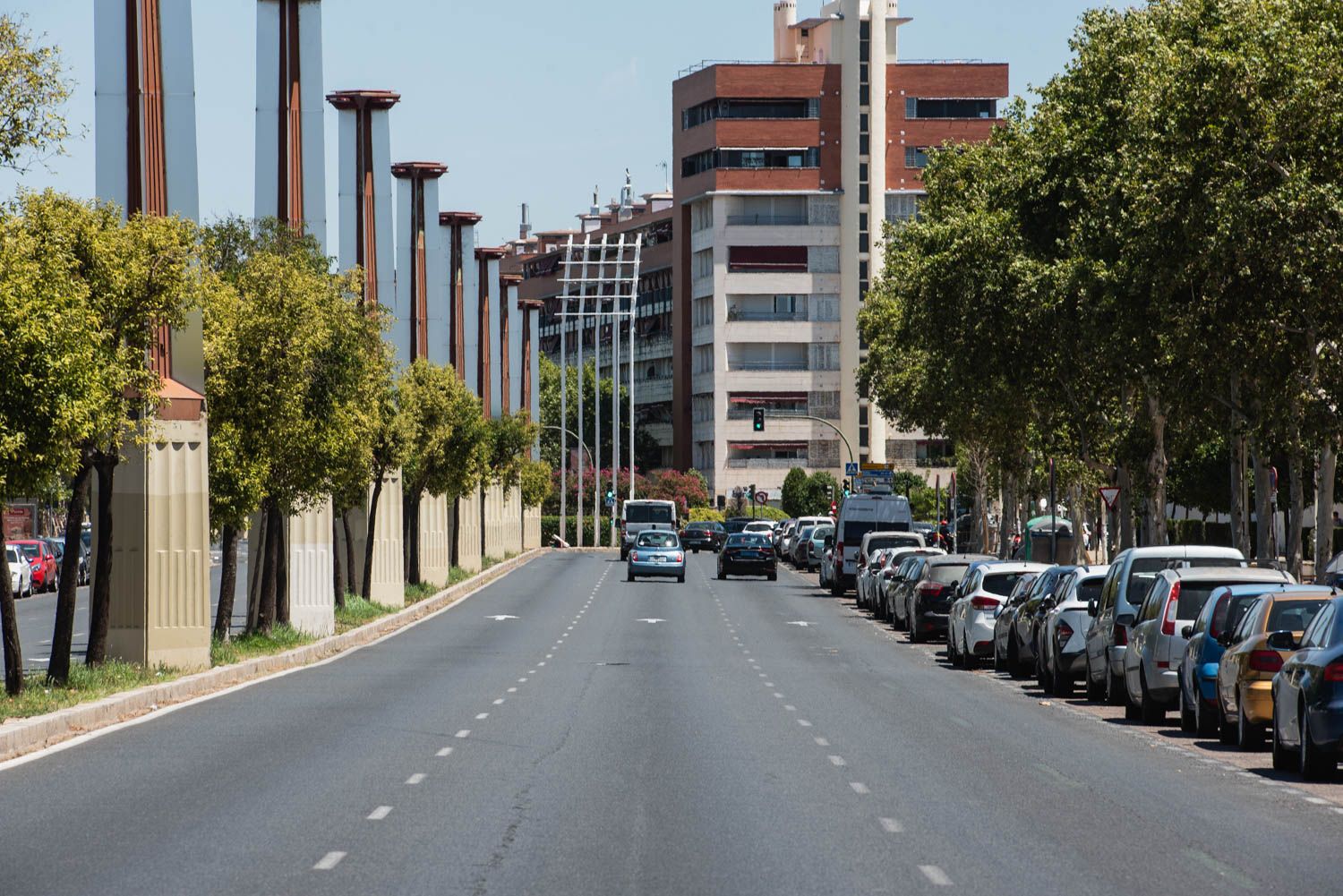 Una avenida de Sevilla con coches aparcados.