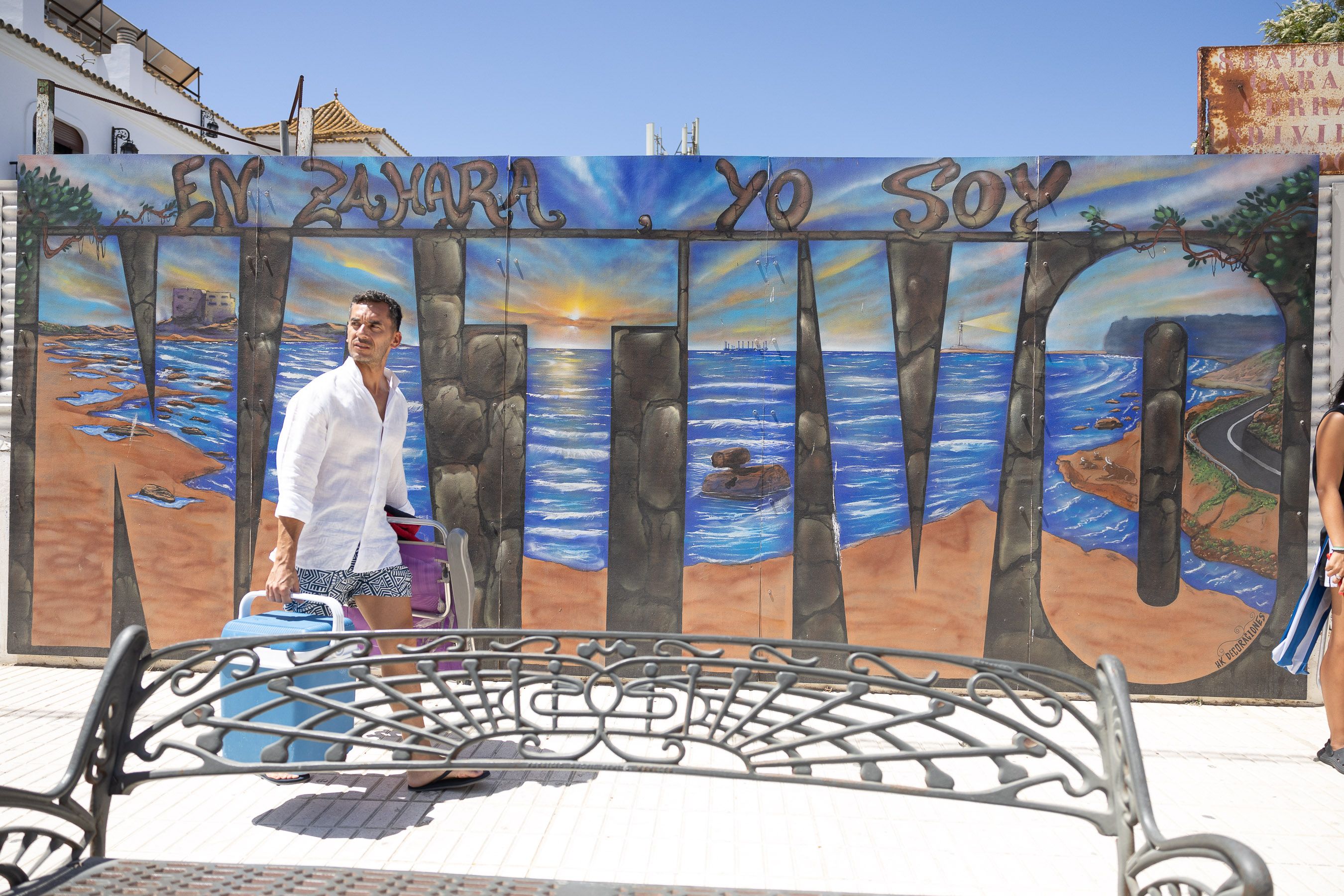 Un turista pasa ante un mural que reivindica al "nativo" en la avenida principal de Zahara de los Atunes.