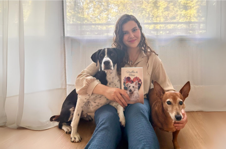 La autora Laura Arcila posa con sus perros (ambos rescatados) y con un ejemplar de su tercera novela, 'Huellas & Flores'. Fotografía cedida.