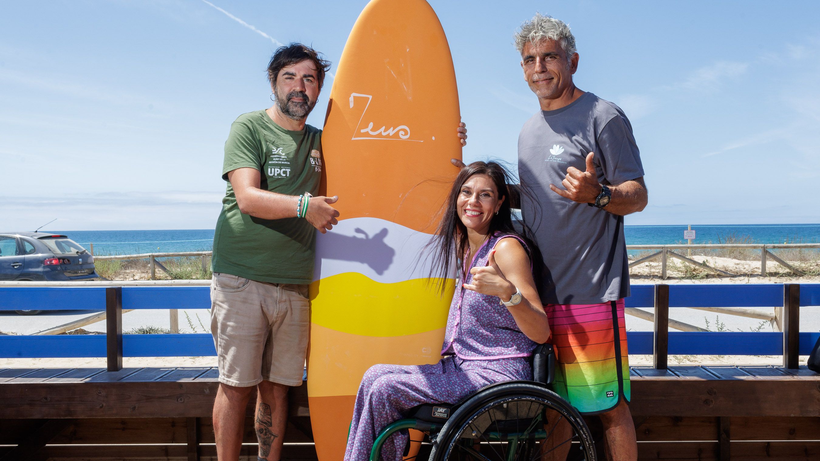 Debora Espinel, en el centro, Ángel Luis Curiel 'Curi', a la izquierda, y Alejandro San Martín, a la derecha, posan en la escuela de surf inclusiva La Troupe, en El Palmar.