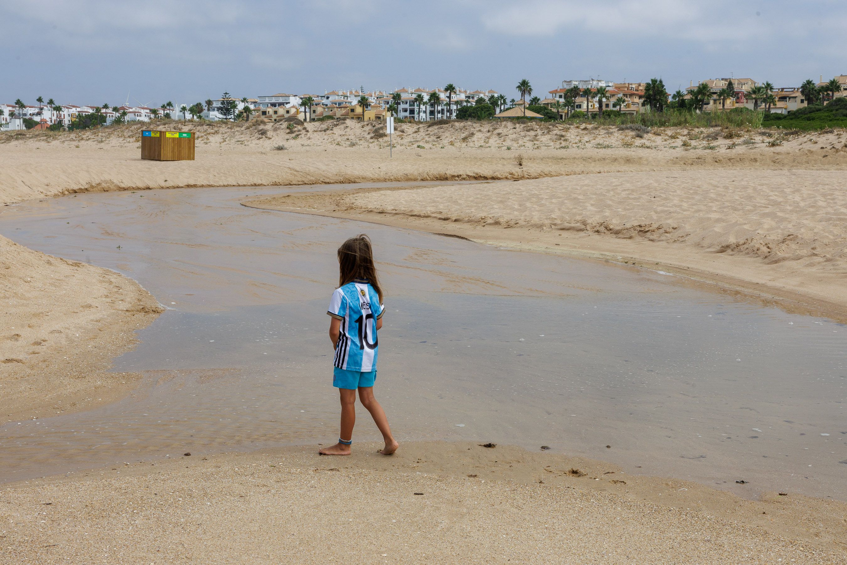 Una niña junto al vertido de aguas residuales que llega a un punto de la playa de Atlanterra, en una imagen tomada este viernes.