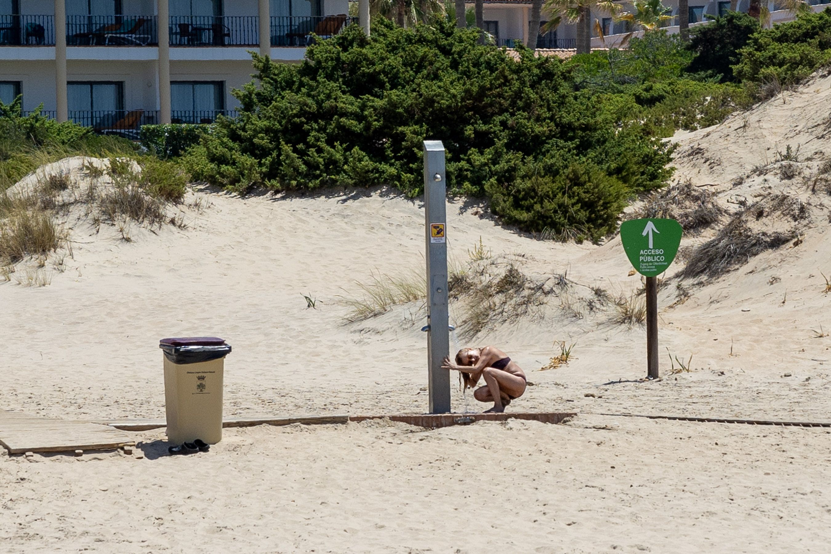 Sequía. Una mujer se lava el pelo en un lavapiés de una playa de Chiclana.