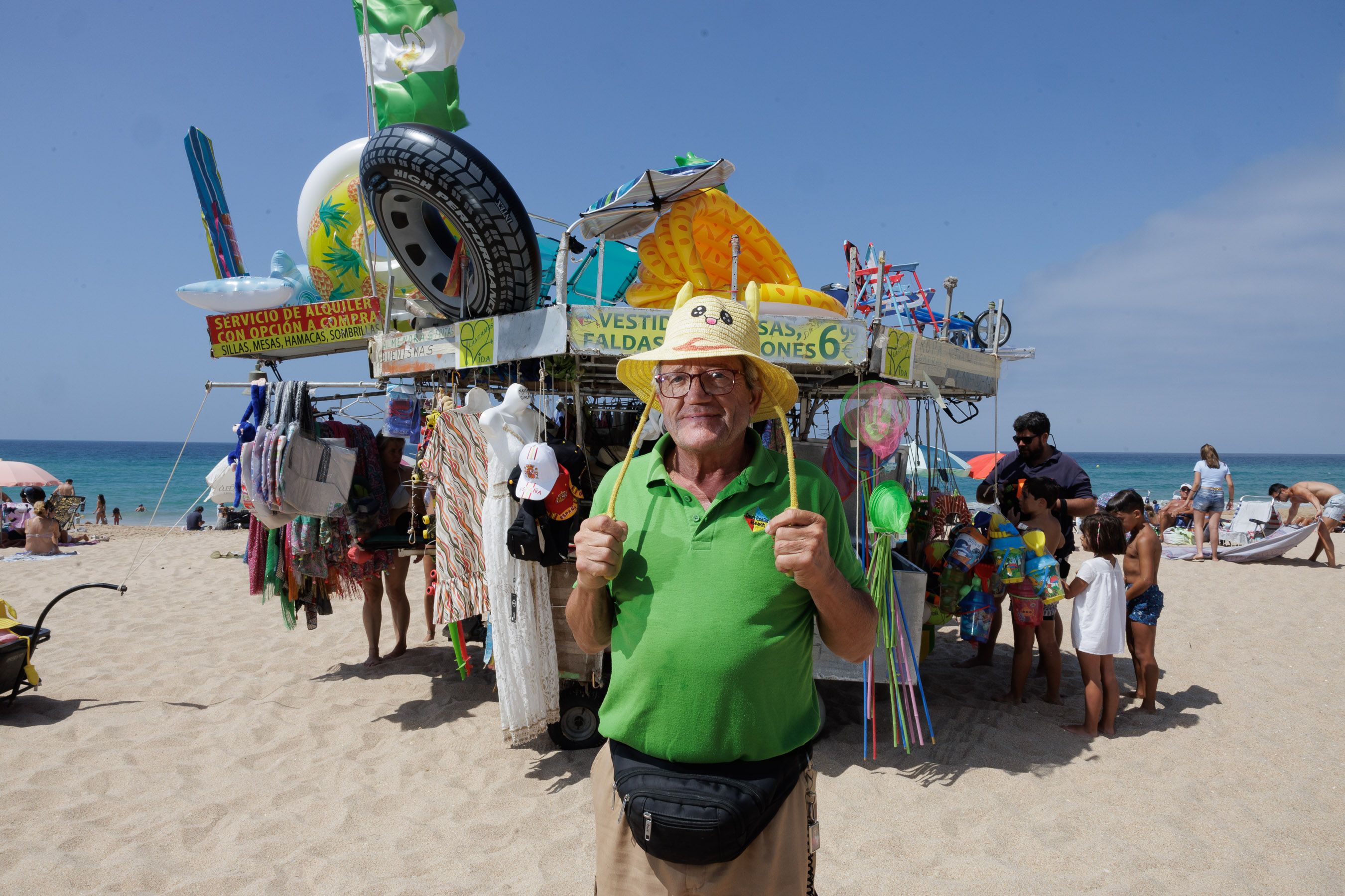 Miguel Ángel, 'El Maño', posa ante su kiosco ambulante en la playa, en el que vende sillas, sombrillas, ropa, bolsos...