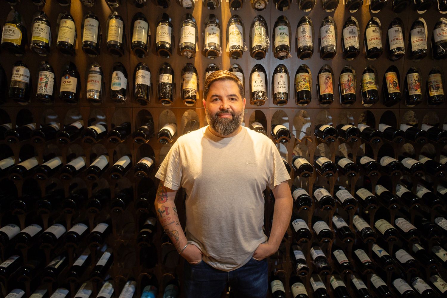 Juanlu Fernández posa con botellas que son obras de arte en LÚ Cocina y Alma.