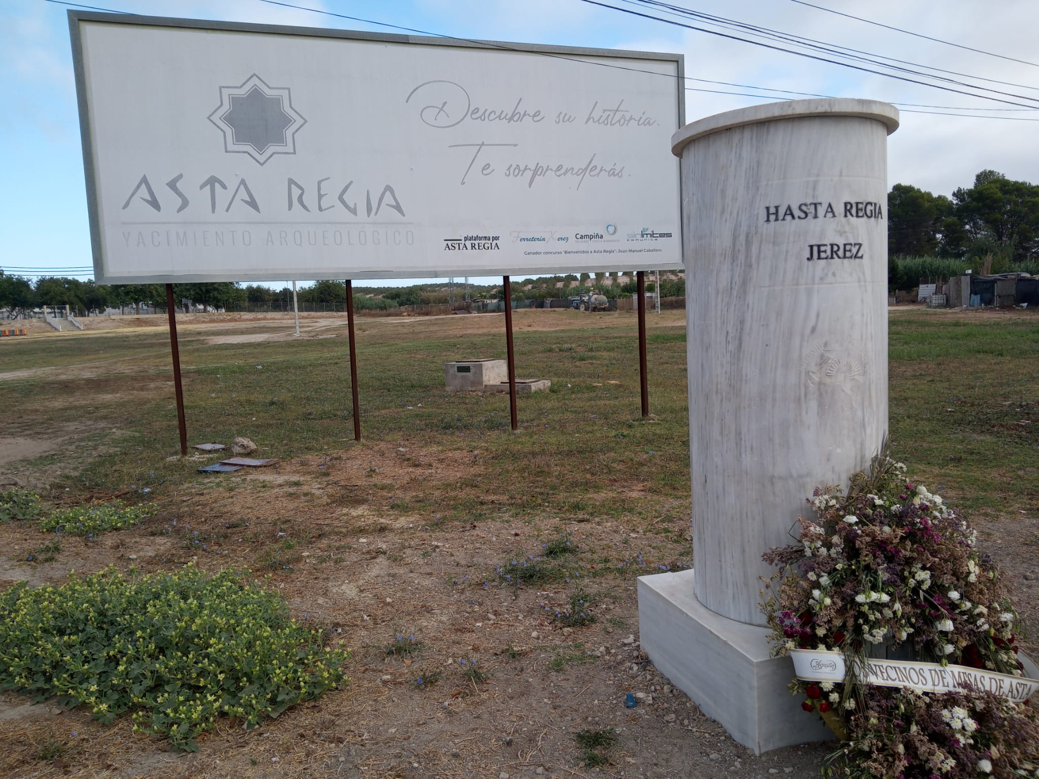 La corona de flores depositada al pie del monolito de Asta Regia.