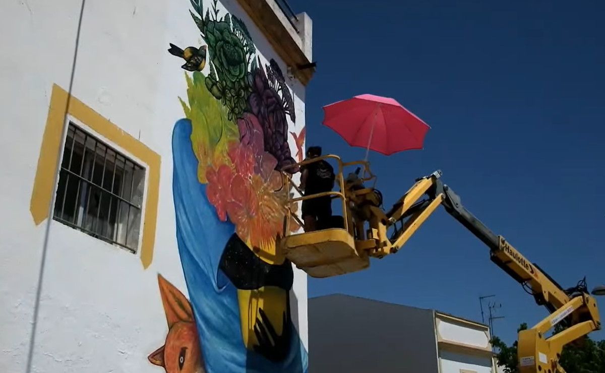 Un muralista pinta la fachada de un edificio en Trebujena.