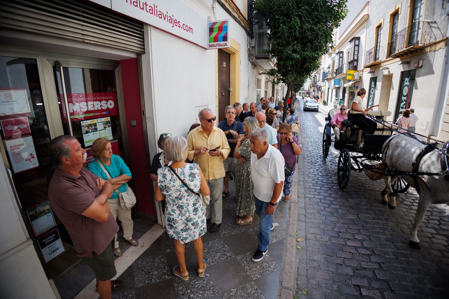 Programa de vacaciones del Imserso. Cola de personas aguardando su turno en la calle Honda.