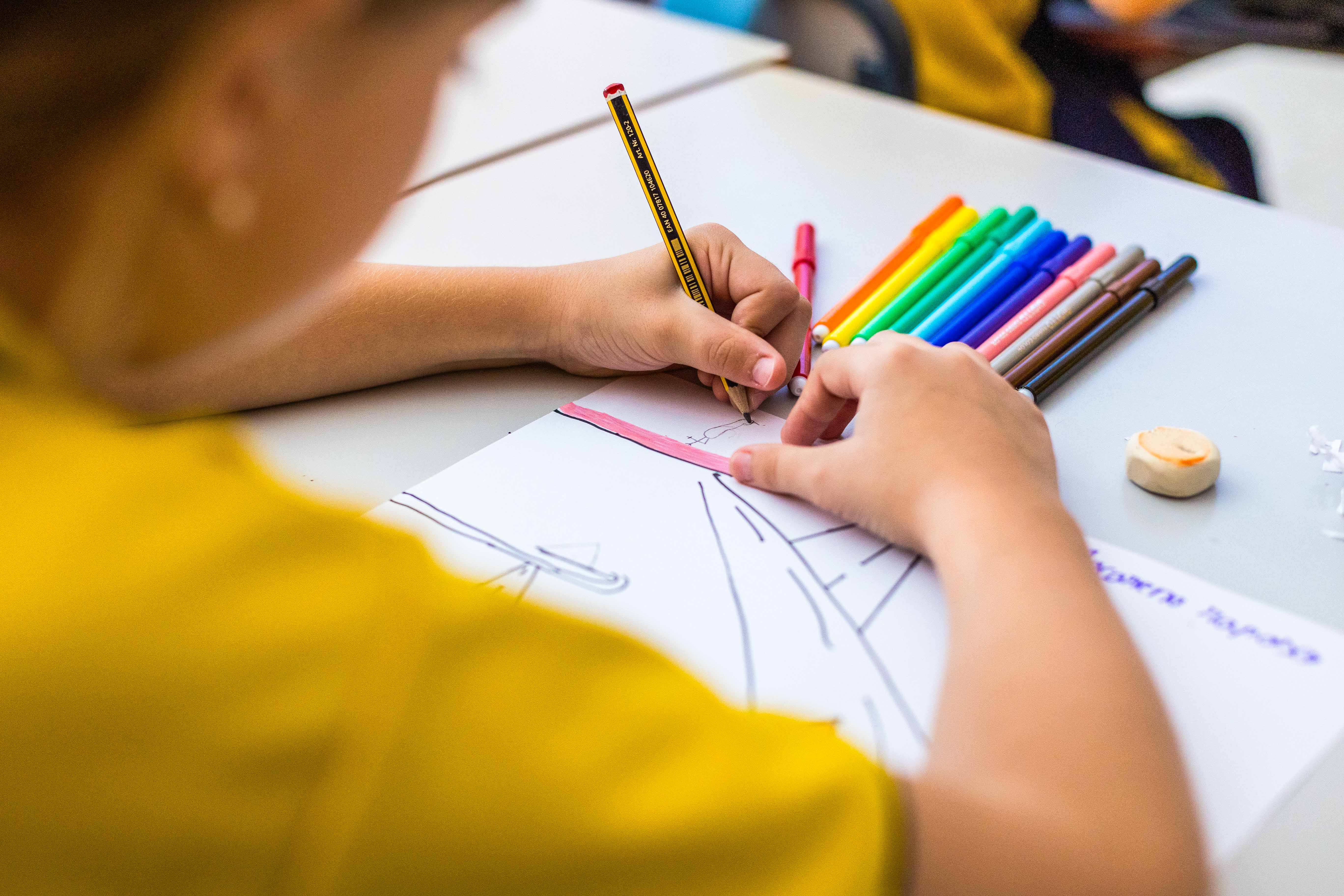 Arranca PequeTAC!. Un alumno en su pupitre dibujando con lápices de colores. 