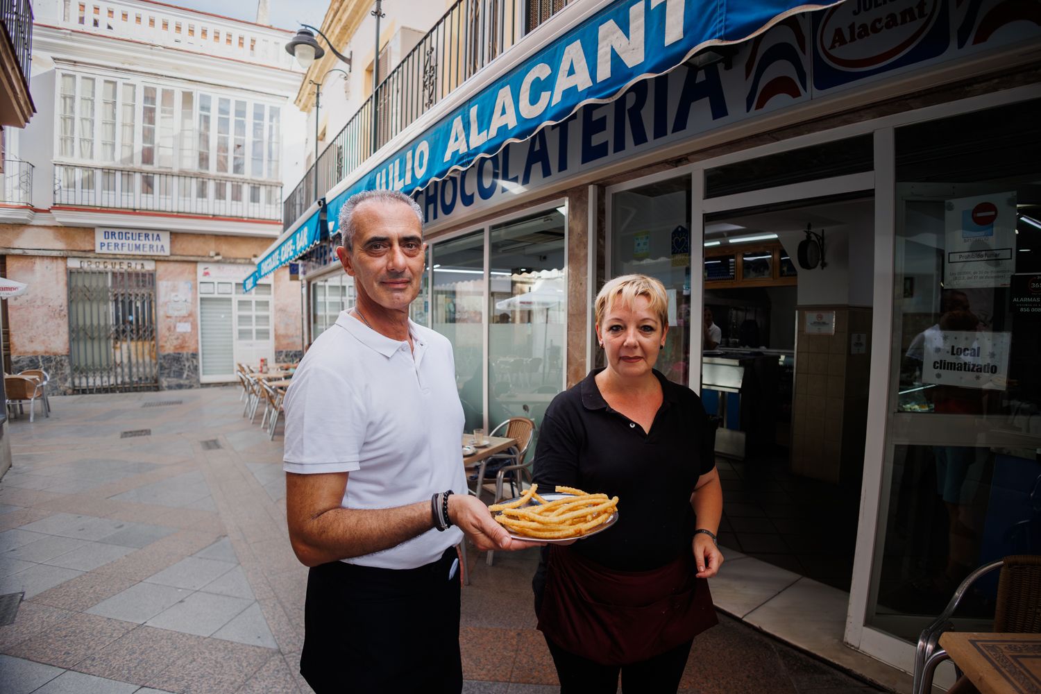 Antonio y Patricia, los gerentes, en la puerta del asbleciiento con una bandeja de churros.