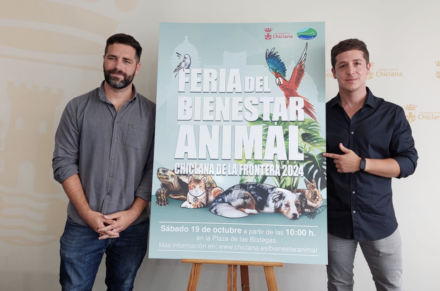 Los delegados junto al cartel que anuncia la Feria de Bienestar Animal.