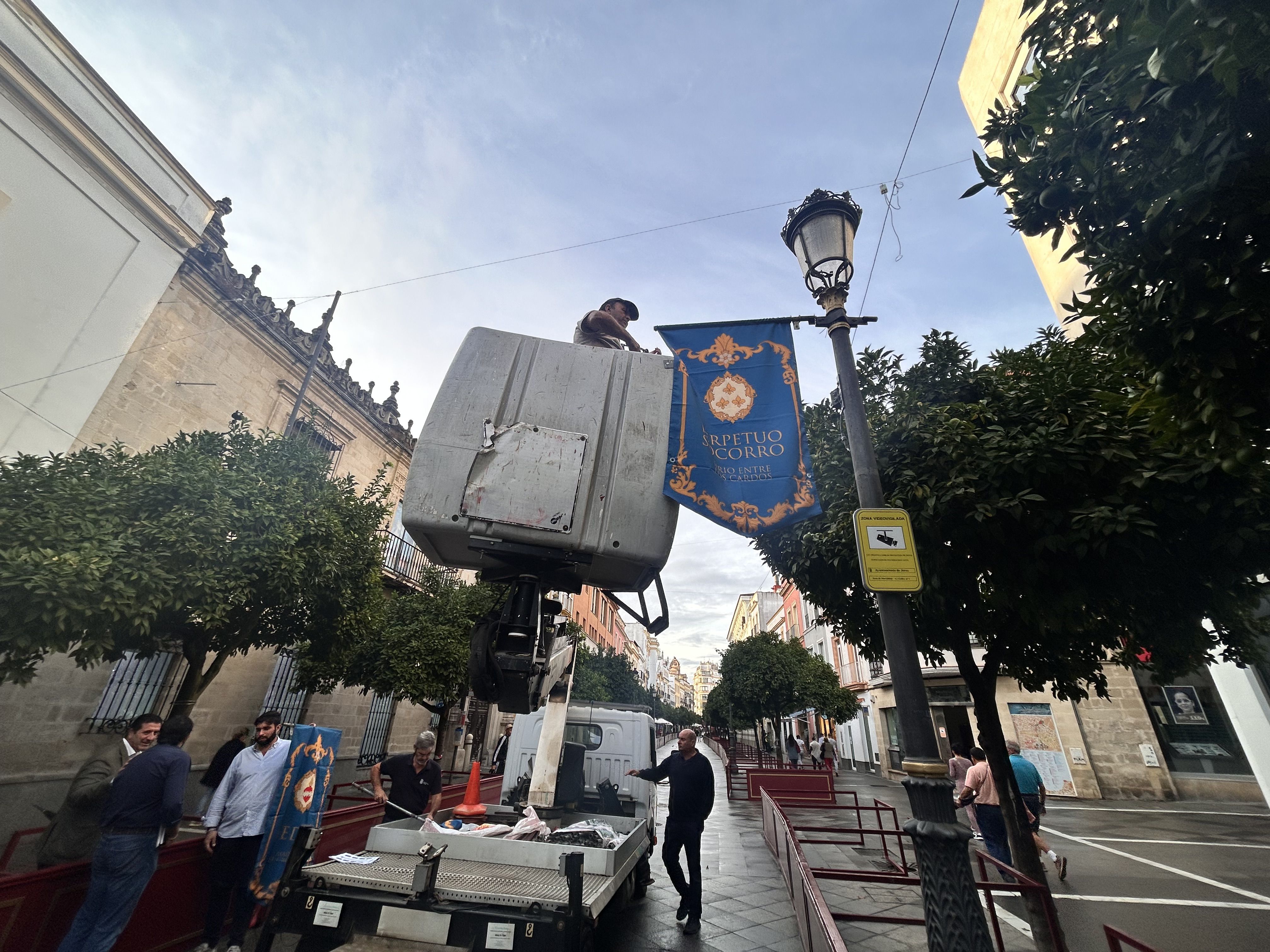 Ocho palios se quedan sin bandas. Un operario municipal colocando esta mañana las banderolas en las farolas de la calle Larga.