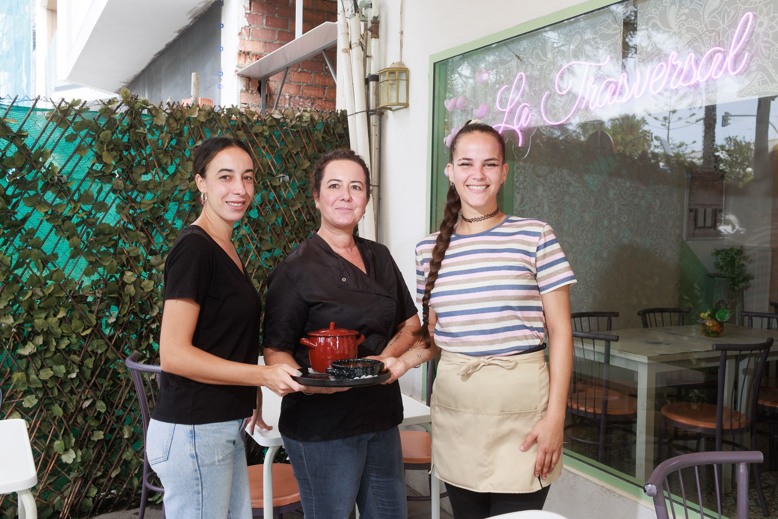 María, Ansi y Carmen con una de las "ollitas" de La Trasversal y las obras a su espalda.