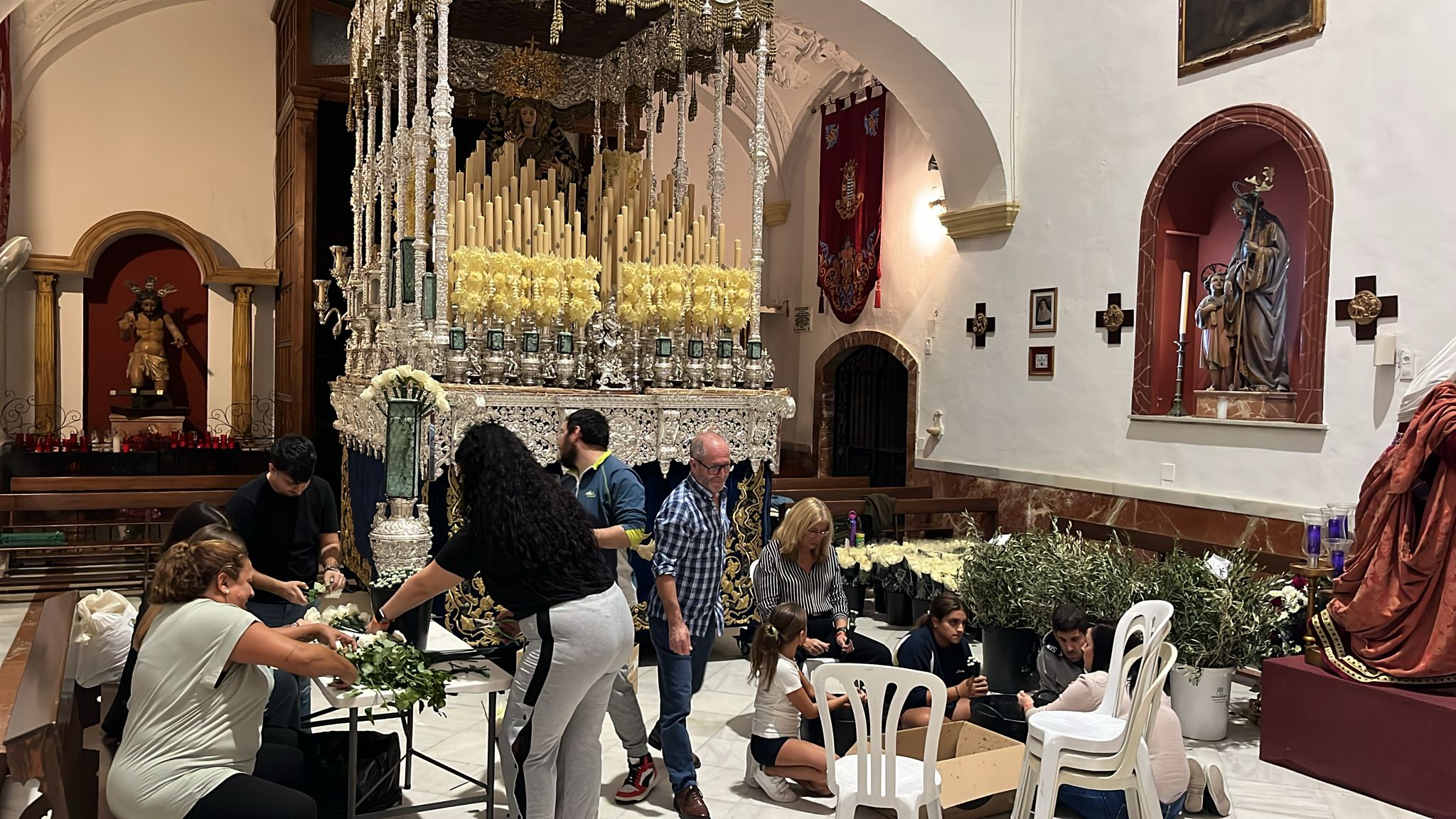 Las hermandades ultiman los montajes. Hermanos y floristas trabajando en la decoración floral del palio de La Paz y Concordia en la Victoria.