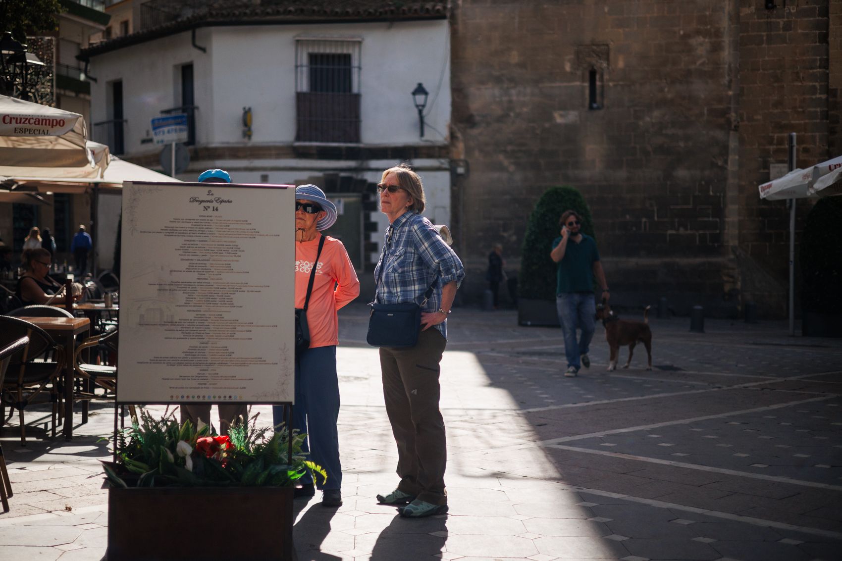 Dos turistas viendo los carteles de un restaurante en plaza Plateros de Jerez.