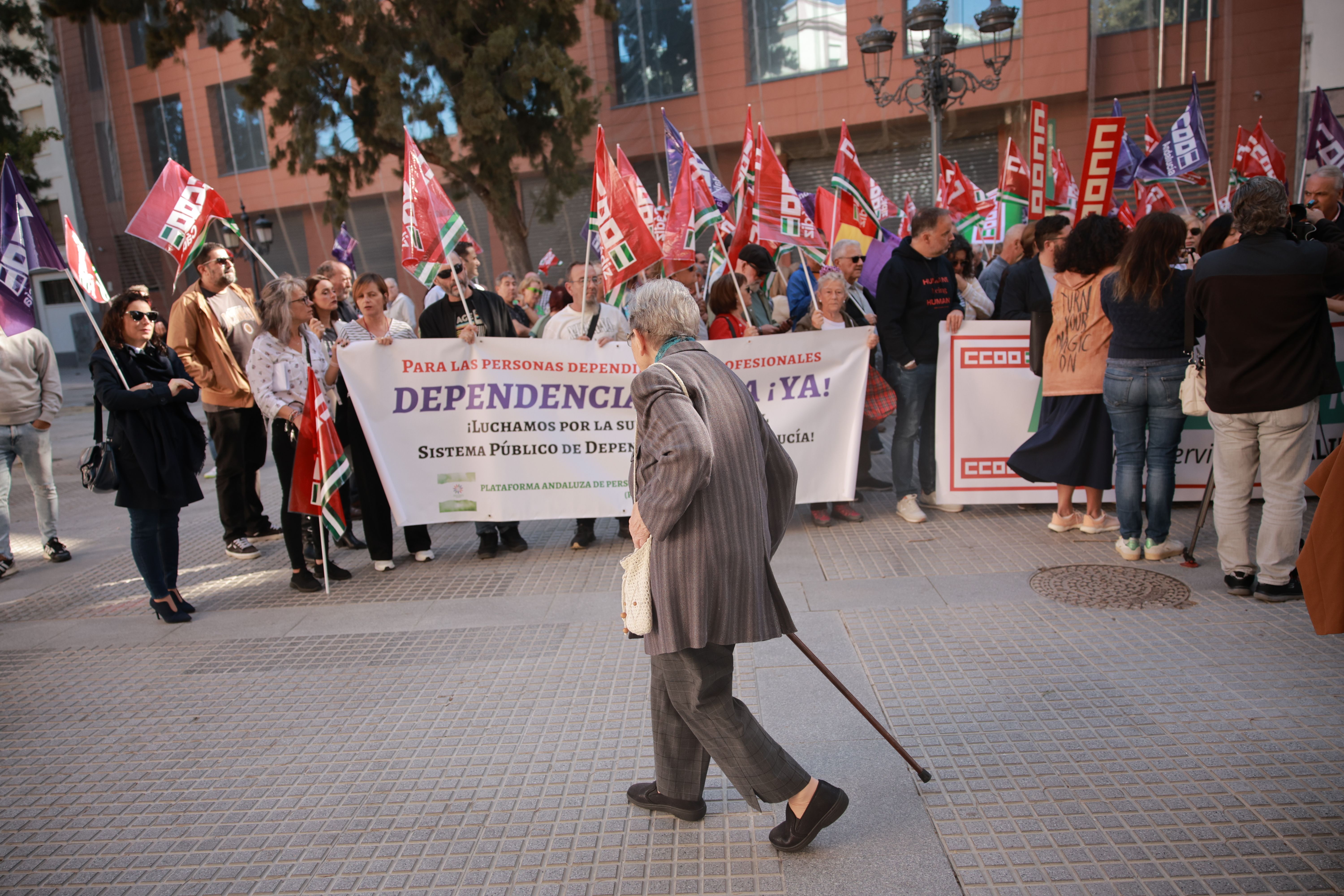 Una mujer pasa frente a la concentración por la dependencia en Cádiz.