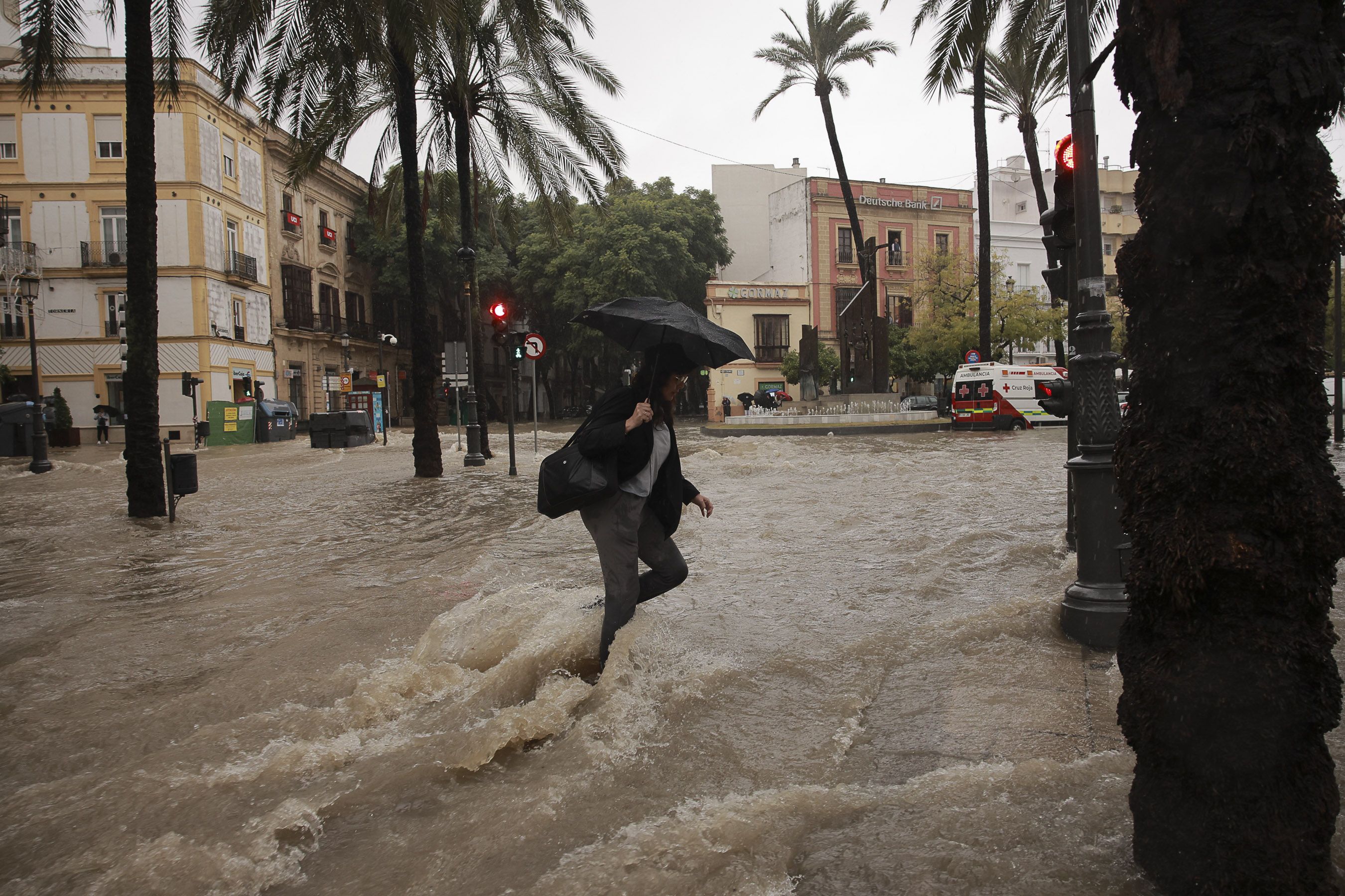 Una mujer intenta cruzar por la Alameda Cristina de Jerez el miércoles, día que supuestamente ha batido el récord histórico por la DANA.