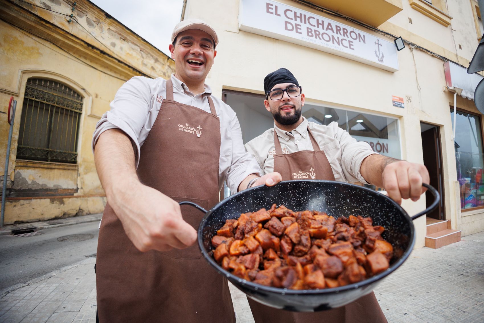 Posando con el perol de chicharrones delante de la puerta del negocio.