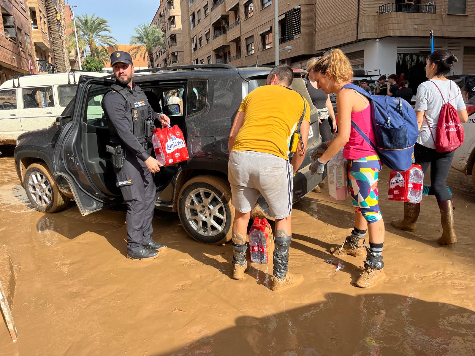 Un agente de la Policía Nacional reparte agua en una zona afectada por la DANA de Valencia.