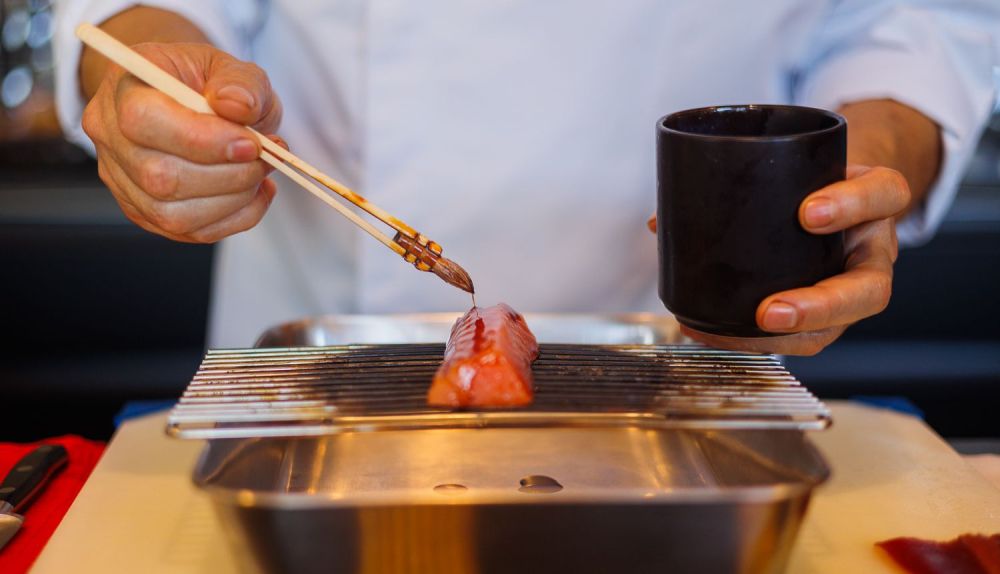 Detalle del sanluqueño pintando el salmón marinado.