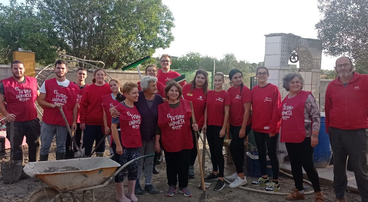 Un grupo de Cáritas joven ayuda a una vecina de El Portal afectada por el desbordamiento de un arroyo.