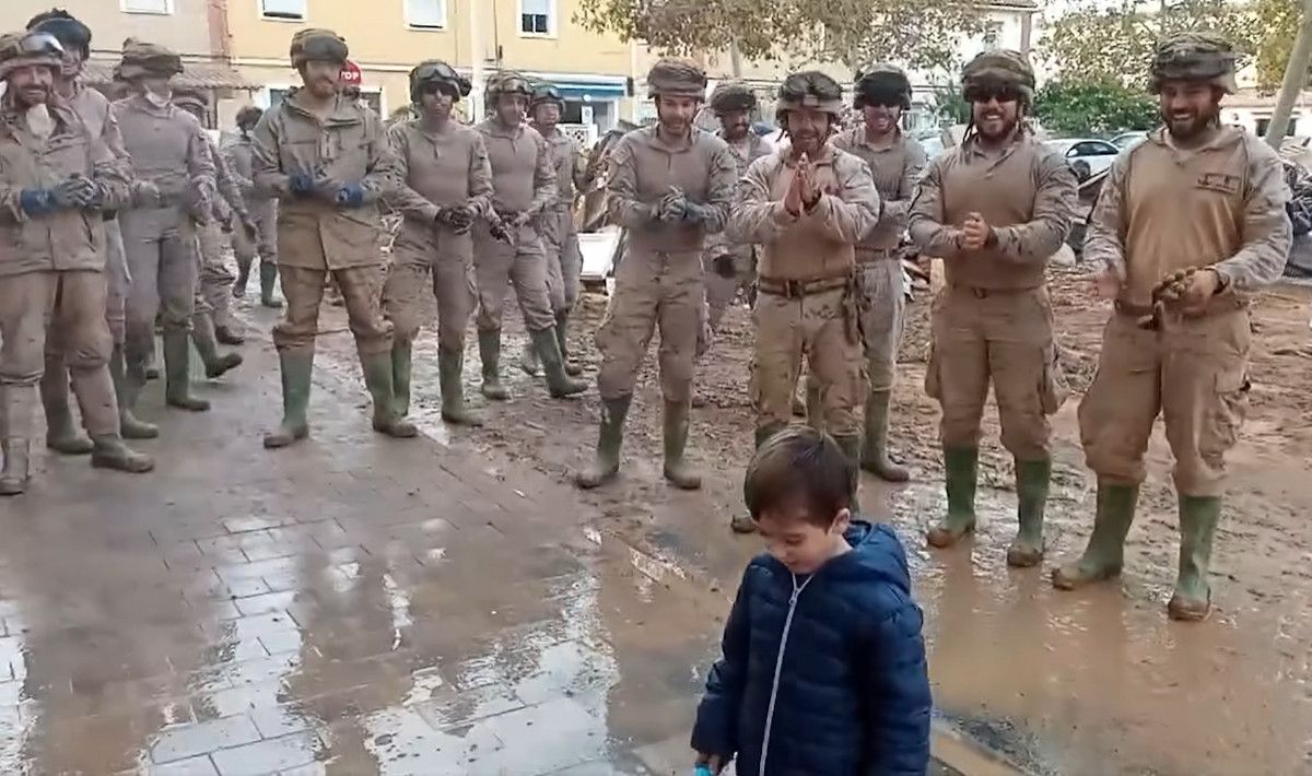 Un grupo de infantes de marina cantan el cumpleaños feliz a un niño en Paiporta. 