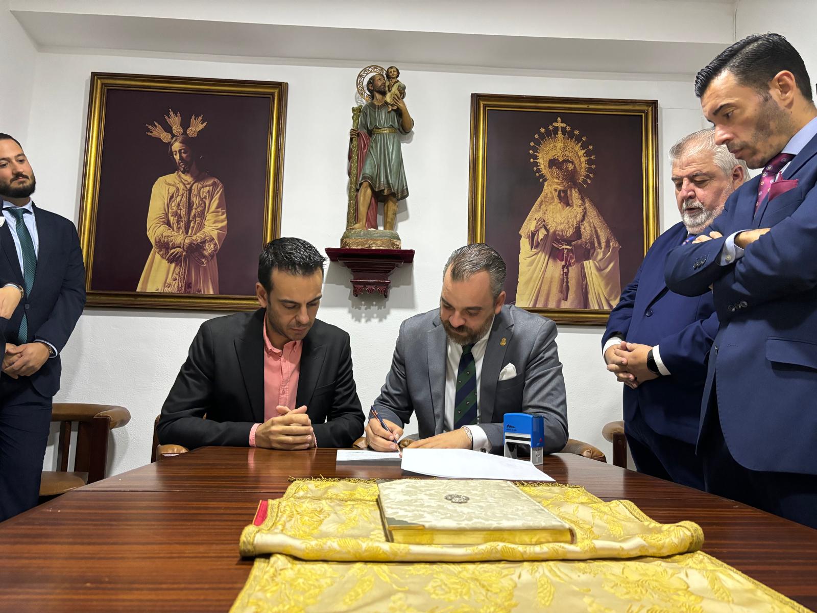 El hermano mayor y el director musical de la Centuria firmando el contrato para el Domingo de Ramos. 