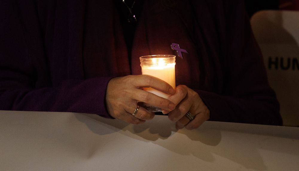 Una mujer sujeta una vela en una manifestación por el 25N.