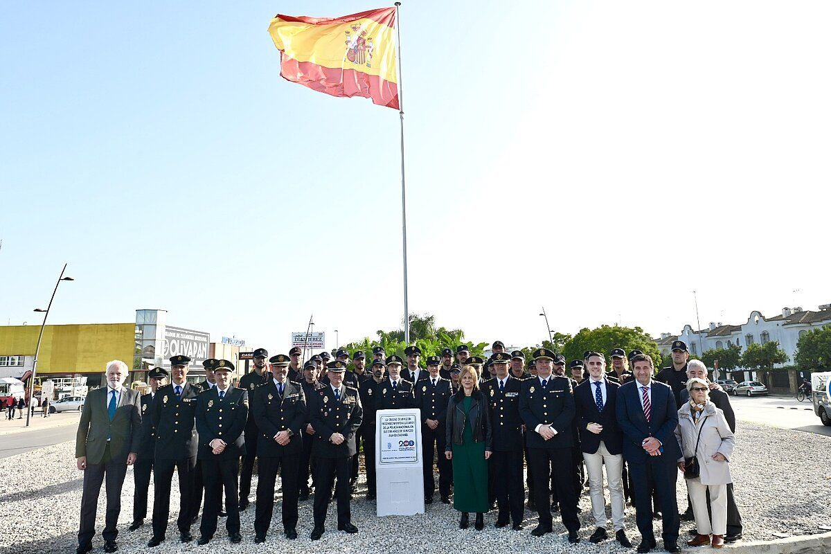 Mandos policiales, agentes del CNP, alcaldesa, delegados y otros invitados en la rotonda donde ondea la bandera de España. 