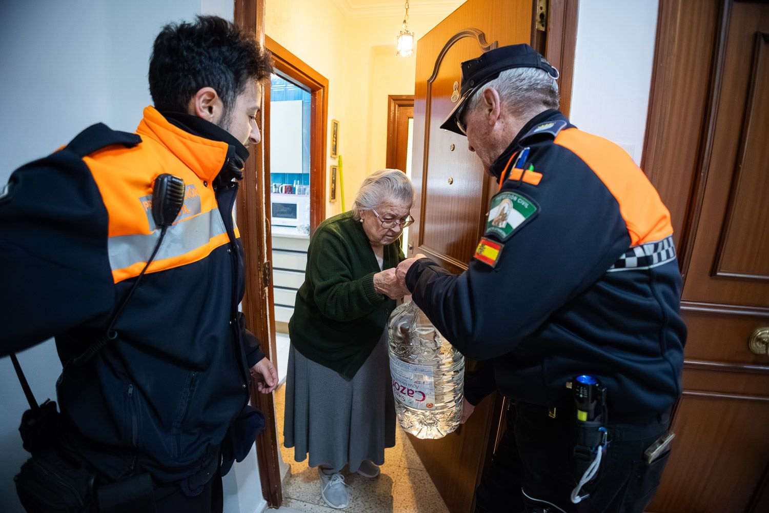 Una vecina de Vallesequillo, recibiendo garrafas de agua de manos de voluntarios de Protección Civil.